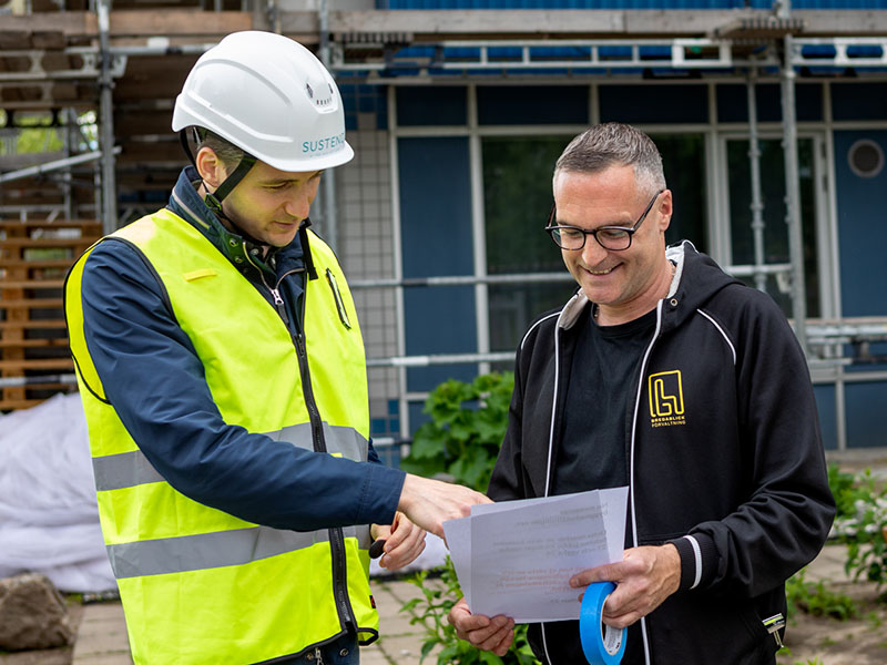 En byggledare och en förvaltare diskuterar renovering av en fasad