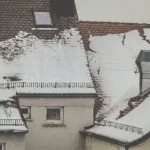 Snö som rasar från ett tak men stoppas av snörasskydd