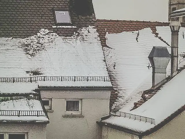 Snö som rasar från ett tak men stoppas av snörasskydd