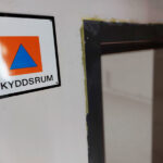 En skylt med texten skyddsrum och skyddsrumssymbolen