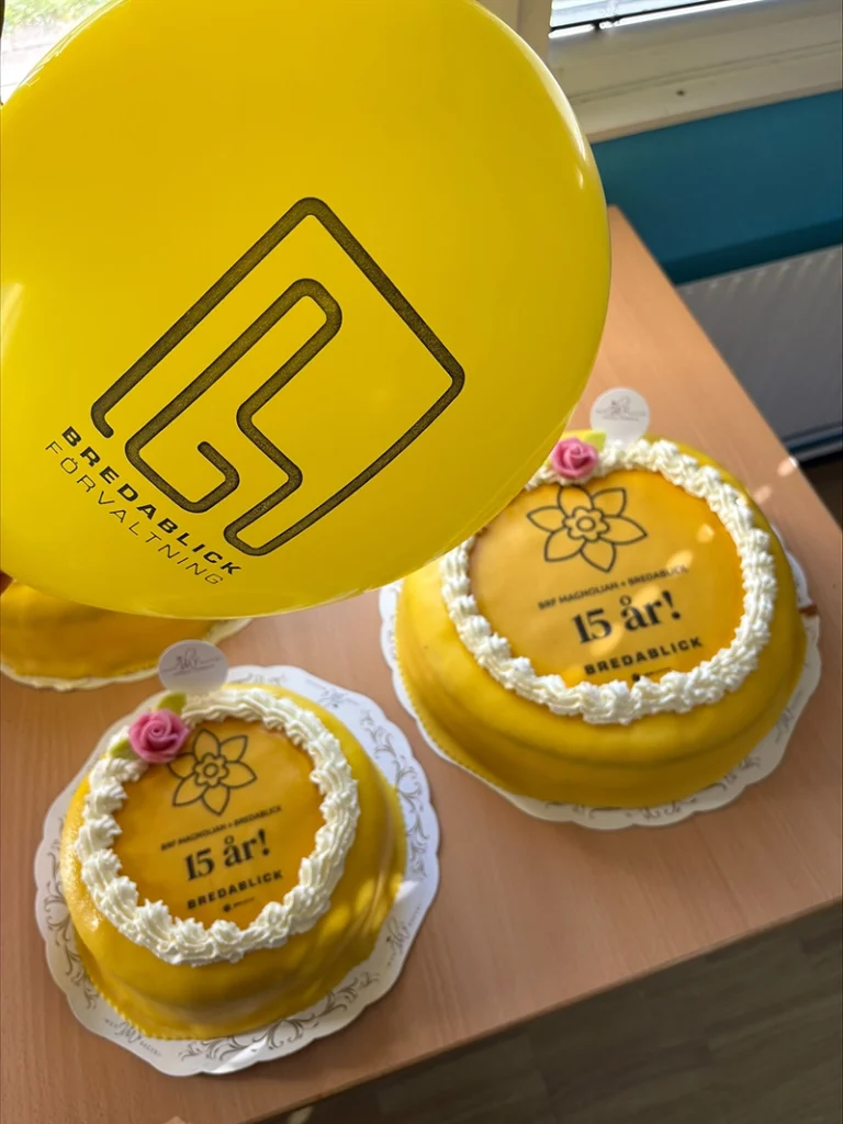 Gula tårtor och ballong med Bredablick Förvaltnings logga.
